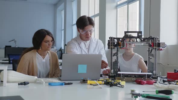 Teacher in White Goggles Shows How to Use and How to Work with the 3D Printer