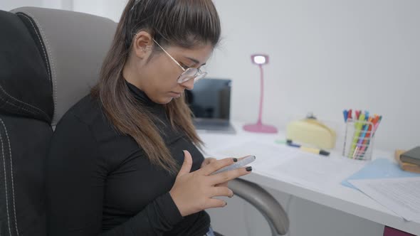 A Young Girl Student of Colombian Universitary Sitting on a Chair and Checking Her Phone