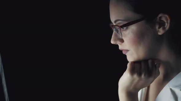 Portrait of a Young Woman Spending Time at the Computer in the Late Evening. Girl with Glasses