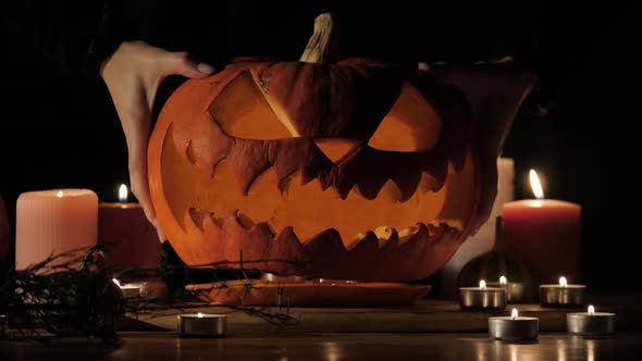 Halloween Pumpkin Head Jack-o-lantern with Burning Candles Over Black Background