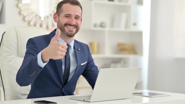 Positive Businessman with Laptop Doing Thumbs Up 