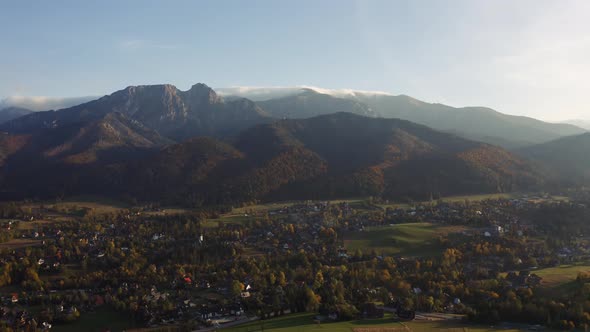 Aerial View Flight Over Mountain Village Lit with Warm Sunlight