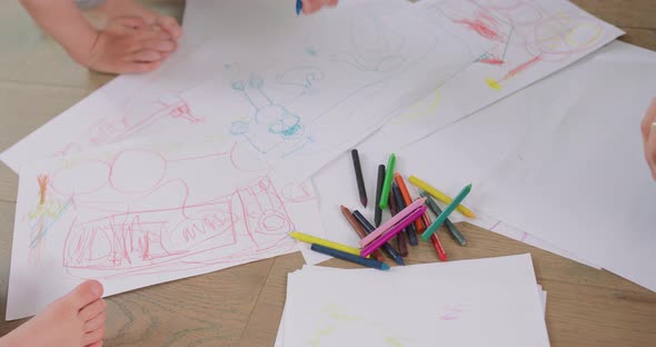 Close Up of a Little Girl's and a Little Boy's Dawings Who are Drawing with Pencils on the White