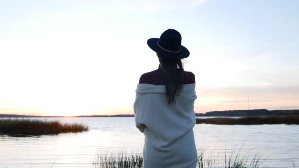 Girl in a Hat and a White Sweater at Sunset Walking