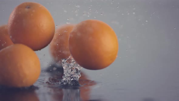 Fresh oranges pass in front of the camera while they bouncing and rolling over in slow motion
