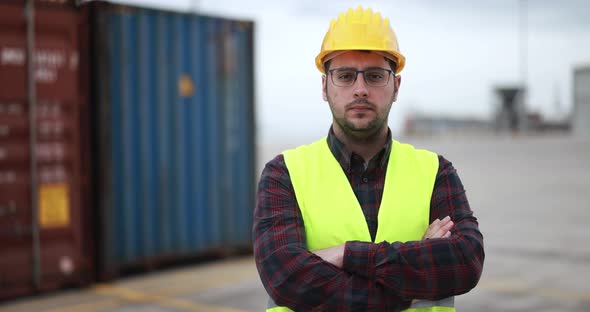 Young man looking on camera working at freight terminal port on background