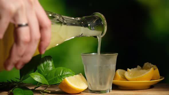 Hand Pouring Limoncello From a Decanter Into a Chilled Glass