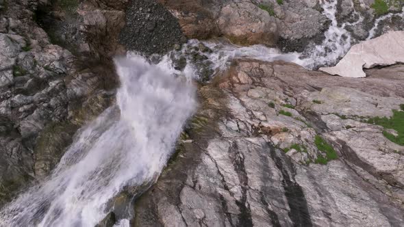 Aerial View Close Up Flight with Mountain Waterfalls Flowing From Glacier Over Rocks