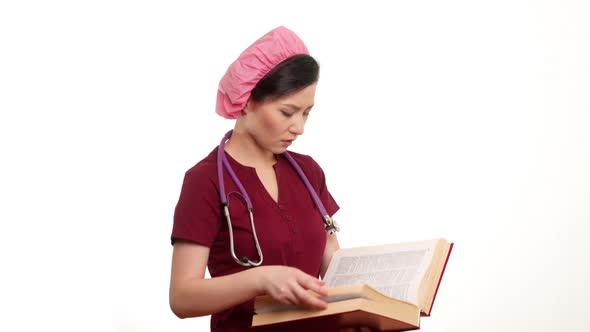 Medium Shot Portrait of Female Doctor in Red Uniform with Stethoscope Reading Medical Book Standing