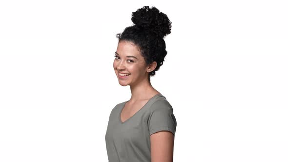 Portrait of Flirty Woman with Curly Bun Hairstyle Blushing and Winking at Camera Isolated Over White