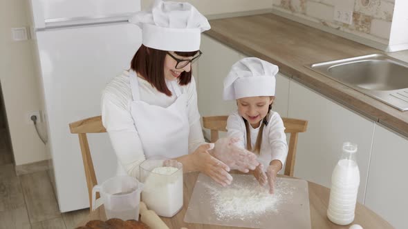 Adorable Little Girl And Her Caucasian Mom in Hats of Chef Clapping Their Hands with Flour