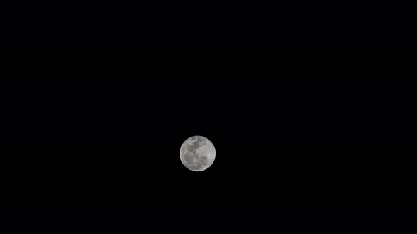 Time lapse of a super full moon as rising in dark sky