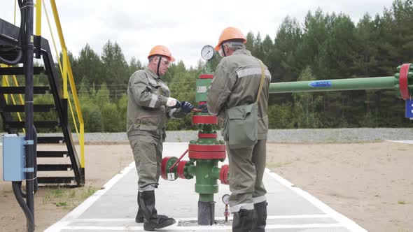 Oil Field Technical Workers Opening or Closing Valve of Wellhead. Injection Tree Is Destined for