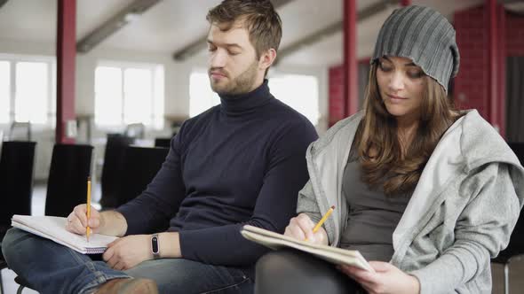 Closeup View of Young Man and Womam Taking Notes During the Presentation