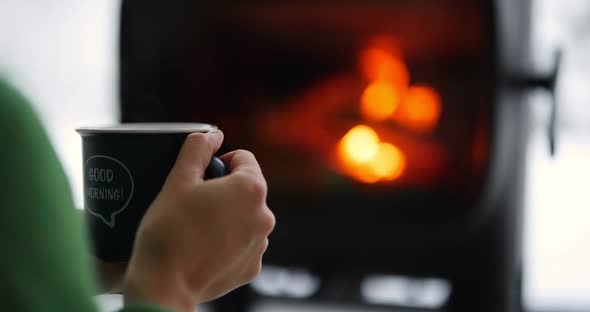 Woman with Hot Drink By the Fireplace in Winter