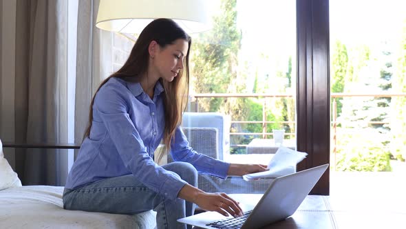 Smiling girl sit on couch watching webinar on laptop. Happy young woman study on online distant cour