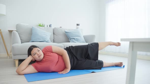 Asian young oversize woman doing yoga exercise by follow Pilates online instructor in living room.