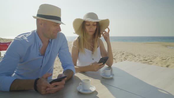 Young Couple Using Mobile Phones on Beach