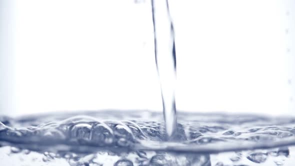 Pouring Water in Glass Kettle on White Background