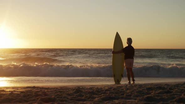 Senior woman with surfboard at the beach