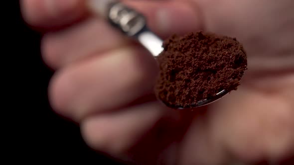 Freshly ground coffee in a dessert spoon in hand