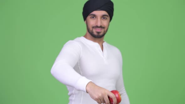 Young Happy Bearded Indian Man Giving Red Apple