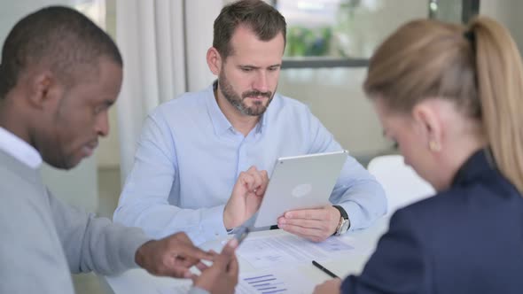 Male and Female Businessperson Working on Tablet and Smartphone in Office