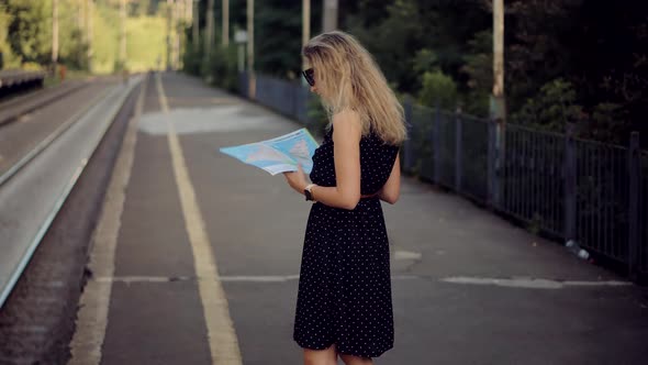 Female Traveler Waiting Train And Looking Town Plan On Navigation Map For Journey.