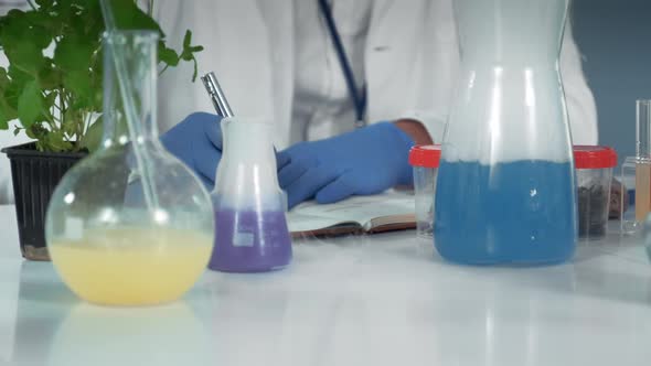 Close-up of Research Scientist Writing Notes in Chemistry Laboratory
