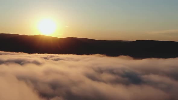 Aerial Drone Footage of Pink Mist Swirls at the Foot of a Mountain Range at Sunset