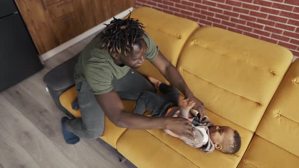 Afro American Dad Playing with Small Kid Boy Tickling Cuddling Together at Home