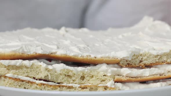 A Woman Puts Cherry Filling On Biscuit Cakes Smeared With Cream.