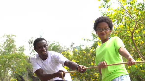 African American Father and Daughter Pulling a Rope Together in Tug of War Competition