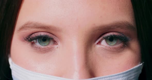 Closeup on the Eyes of a Woman Wearing a Medical Face Mask Looking at the Camera