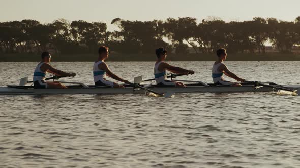 Side view of male rower team rowing on the lake