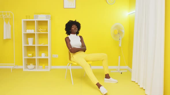 Portrait of Black Woman Sitting On Yellow Chair