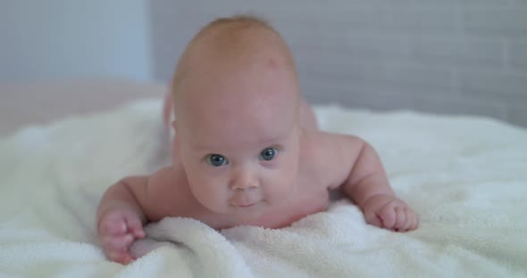 Funny Reaction Into Camera of Cute Newborn Baby on Bed