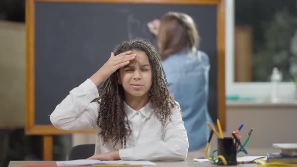 Portrait of Sad Exhausted African American Schoolgirl Falling Asleep Sitting at Desk in Classroom