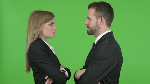 Male and Female Professional Looking at Each Other Against Chroma Key