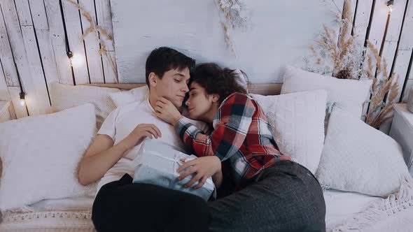 Romantic Young Couple Embracing While Sitting on the Bed in the Bedroom on Christmas Eve