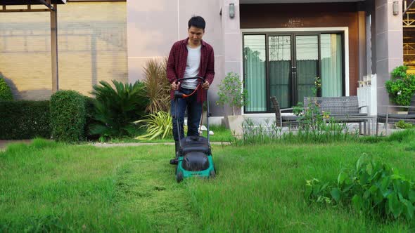 man using a lawn mower cutting grass at home