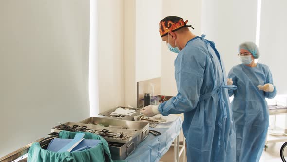 Operating Room of Surgical Table with Instruments Doctor Picks Up Instruments
