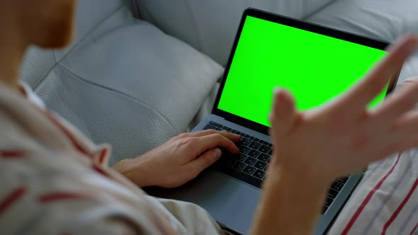 Man Talking Green Laptop Resting on Sofa Closeup