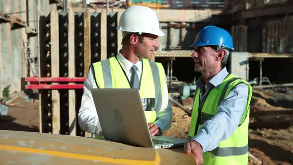 Mature men using laptop on construction site