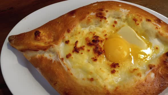 Adjarian Khachapuri on a Table in a Georgian Restaurant. Open Bread Pie with Egg Yolk