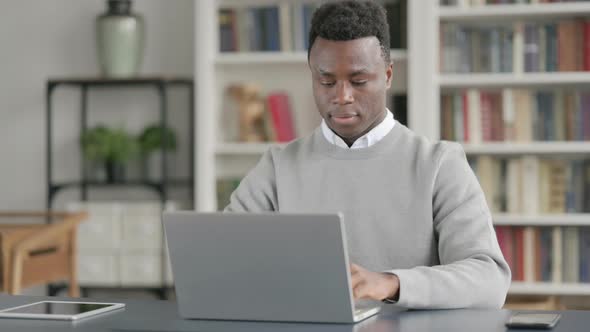 African Man Showing Thumbs Up Sign While Using Laptop at Work