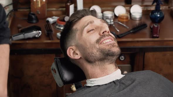 Professional Barber Cutting Beard of Handsome Man