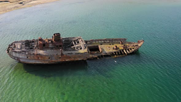 A Wrecked Wooden Ship Lies on the Seashore Covered with Rust