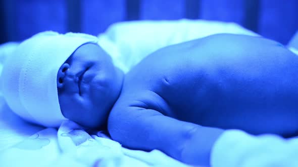 Newborn Having a Treatment for Jaundice Under Ultraviolet Lamp in Home Bed