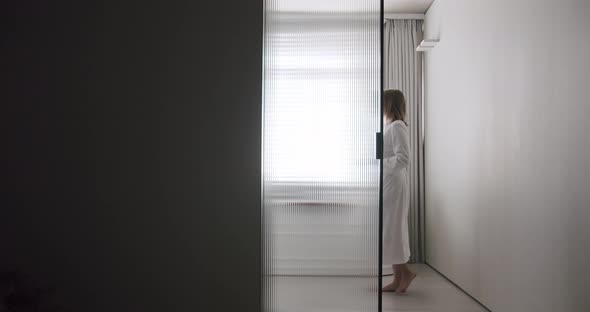 Woman in Robes Open Transparent Sliding Door Inside the Modern Bathroom